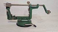 Side view of green mechanical apple peeler showing full mechanism
