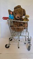 Mini shopping cart holding two plush bears and a doll