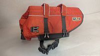 Side view of orange Outward Hound life jacket showing logo, handles, buckles