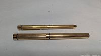 Both pens capped showing matching fluted gold-tone finish