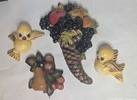 All four plaques laid out: cornucopia, fruit cluster, two yellow birds