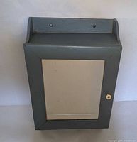 Front view of medicine cabinet showing mirrored door, knob, towel bar