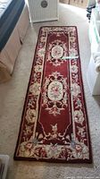 Top view of entire garnet floral runner rug on carpeted floor