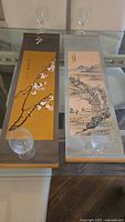 Both scrolls laid flat on glass table, showing overall size and designs
