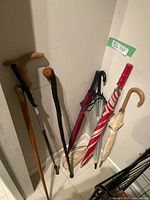 Group of three canes and five umbrellas standing in corner