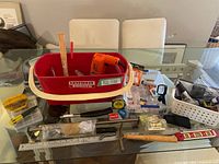 Overall lot view with tub containing drill, hammer, level, measuring tapes, hardware