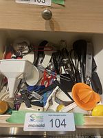 Drawer view showing mixed utensils including funnel, whisks, scissors, citrus reamer