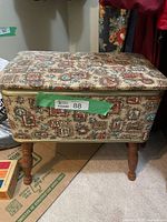 Closed vintage upholstered sewing box on four turned legs