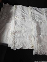 White embroidered scallop-hem panels folded on surface