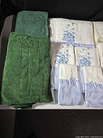 Solid green bath towel next to white towels with blue bunny embroidery