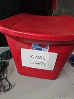 Red plastic storage bin with lid labeled X-MAS LIGHTS