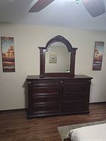 Dresser with mirror centered between two canvases on wall
