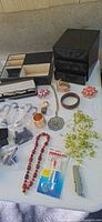 Table overview with jewelry organizer, pendant necklace, bangles, bead strand, pocketknife, watch cement tube
