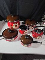 Red floral enamel cookware set displayed