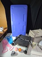 Overview showing blue storage lid, stair stepper, boot shapers, stress ball, ointment jar, cord and step stool