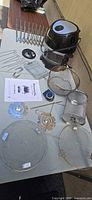 All components laid out including air fryer base, lid, glass bowl, mesh drum, racks, skewers and manual