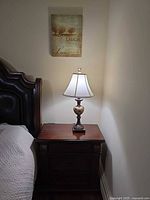 Nightstand beside bed showing lamp and canvas