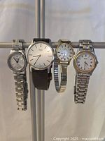 All four watches hanging on stand, front view