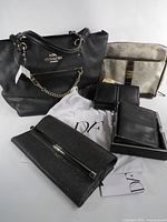 Group shot of Coach tote, DVF clutch, Samsonite cosmetic bag, two wallets and DVF dust bag