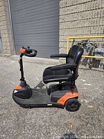Left side view of scooter showing overall form, seat, armrests, tiller, wheels