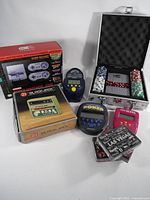 Group shot showing SNES Classic box, poker chip case open, handheld games, 21 Blackjack box, card decks