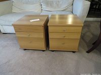 Front view of two matching light wood veneer 3-drawer nightstands on casters