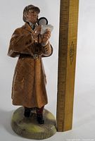 Full front view of figurine beside ruler showing height