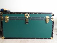 Front view of green trunk with brass hardware and black trim