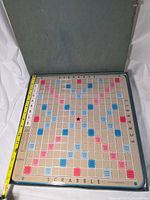 Open case showing full Scrabble board with measuring tape for size reference