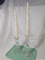 both candlesticks with candles on tray against backdrop