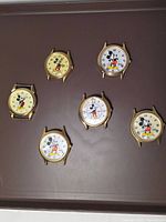 Front view of six Mickey Mouse watch faces showing dial colors and character design