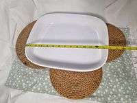 Top view of casserole dish positioned on three woven trivets with tape measure across width