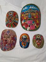 Group shot of five Mexican clay masks laid on white cloth