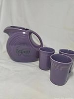 Lavender Fiesta pitcher with three tumblers front view