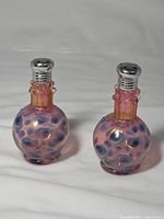 Two matching pink and blue art glass shakers front view