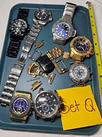 Top view of tray showing eight Invicta watch heads and loose parts