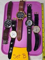 Front view of five Invicta watches on tray, showing dial designs and strap colors