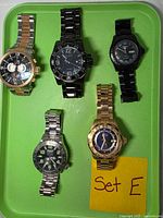 Front view of all five Invicta watches on green tray