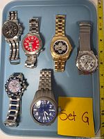 Six Invicta watches face up on tray showing dial designs and finishes