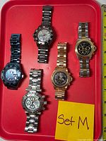 Top view showing five Invicta wristwatches on red tray