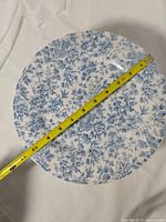 Top view of patterned dinner plate with tape showing diameter ~10 in.