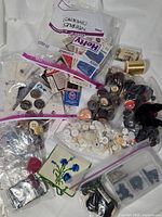 Overview of bags containing buttons, needles, floss and thread