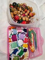 Wooden beads in clear plastic tub next to pink organizer with embroidery floss