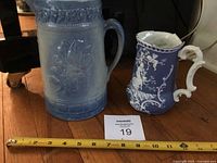 Both pitchers side by side with measuring tape and lot card