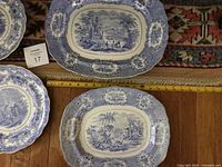 Two oval blue transferware platters with scenic design and gold trim