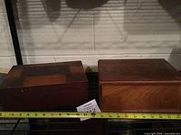 Both wooden boxes side by side with measuring tape for scale