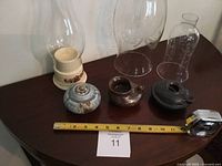 Group view of three pottery oil lamps and three glass chimneys