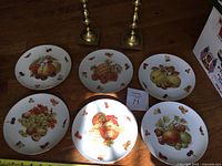 All six fruit plates arranged with two brass candlesticks visible