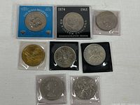 Overview of seven packaged commemorative coins and medal