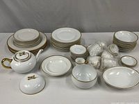 Group view of entire dinnerware lot showing stacks of plates, bowls, teapot, bubble-wrapped pieces